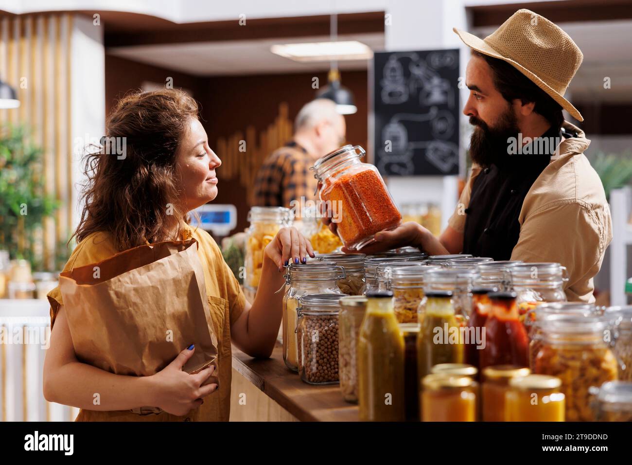 Entrepreneur de magasin zéro déchet montrant ses produits sans produits chimiques naturels à un client intéressé par un mode de vie à faible impact sur la planète. Propriétaire de supermarché EcoFriendly présentant sa marchandise au client Banque D'Images