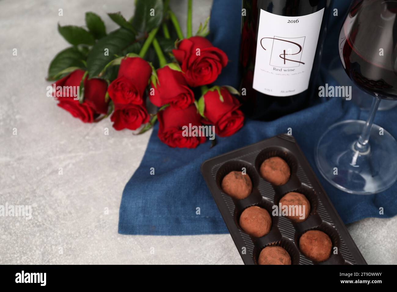 Vin rouge, truffes au chocolat et roses sur table texturée légère, gros plan Banque D'Images