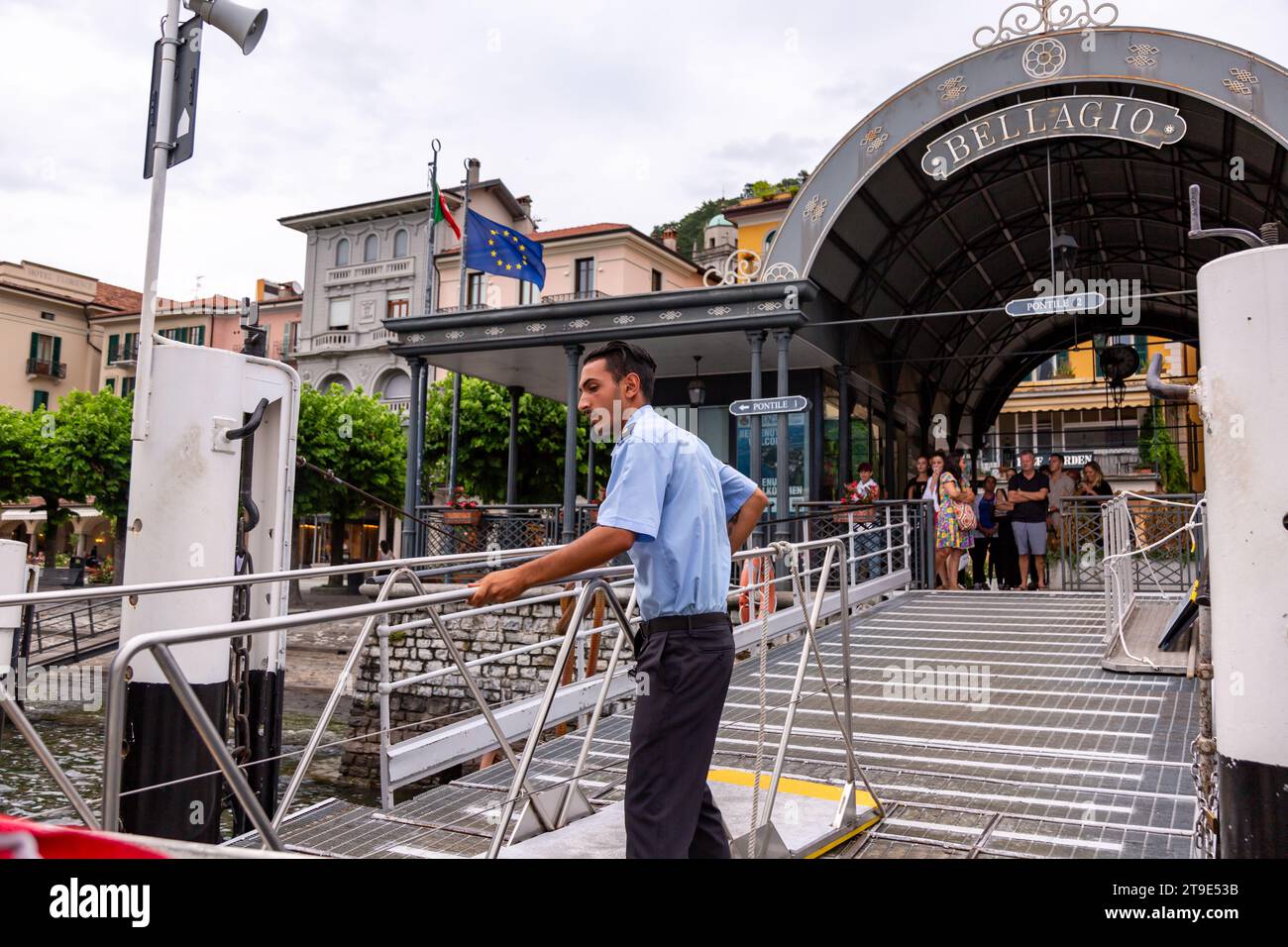Les passagers attendent un matelot de pont en uniforme Navigazione Laghi alors qu'il déplace une passerelle en place au terminal de ferry du lac de Côme à Bellagio, Lombardie, Italie. Banque D'Images