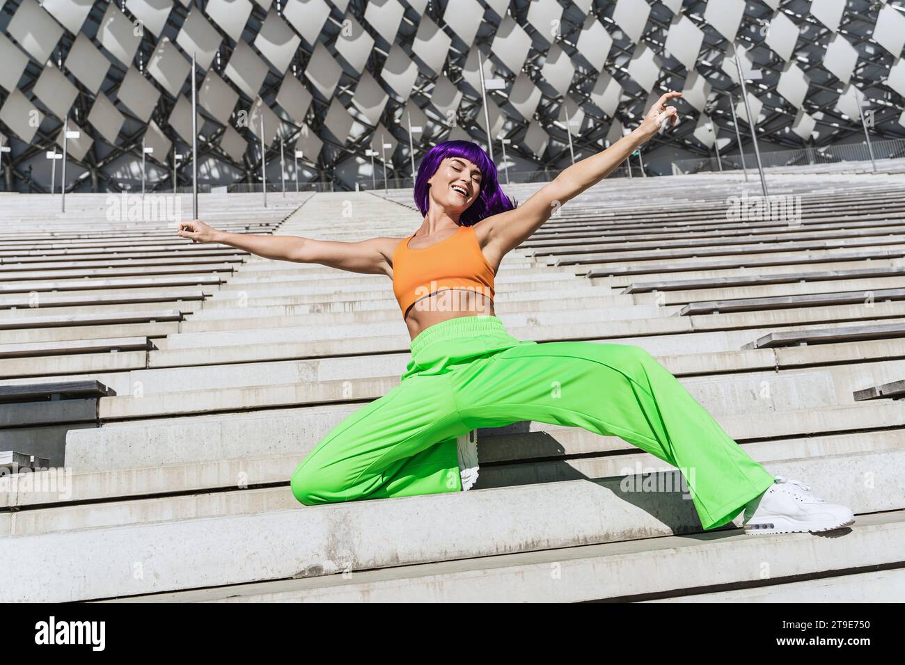 Danseuse femme active portant des vêtements de sport colorés se produisant dans la rue pendant la journée d'été Banque D'Images