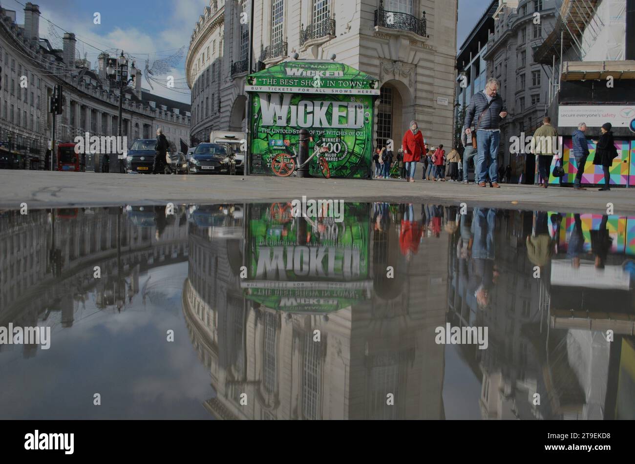 Reflet de la flaque d'eau de Regents Street et kiosque à billets avec une publicité pour la comédie musicale Wicked. Banque D'Images