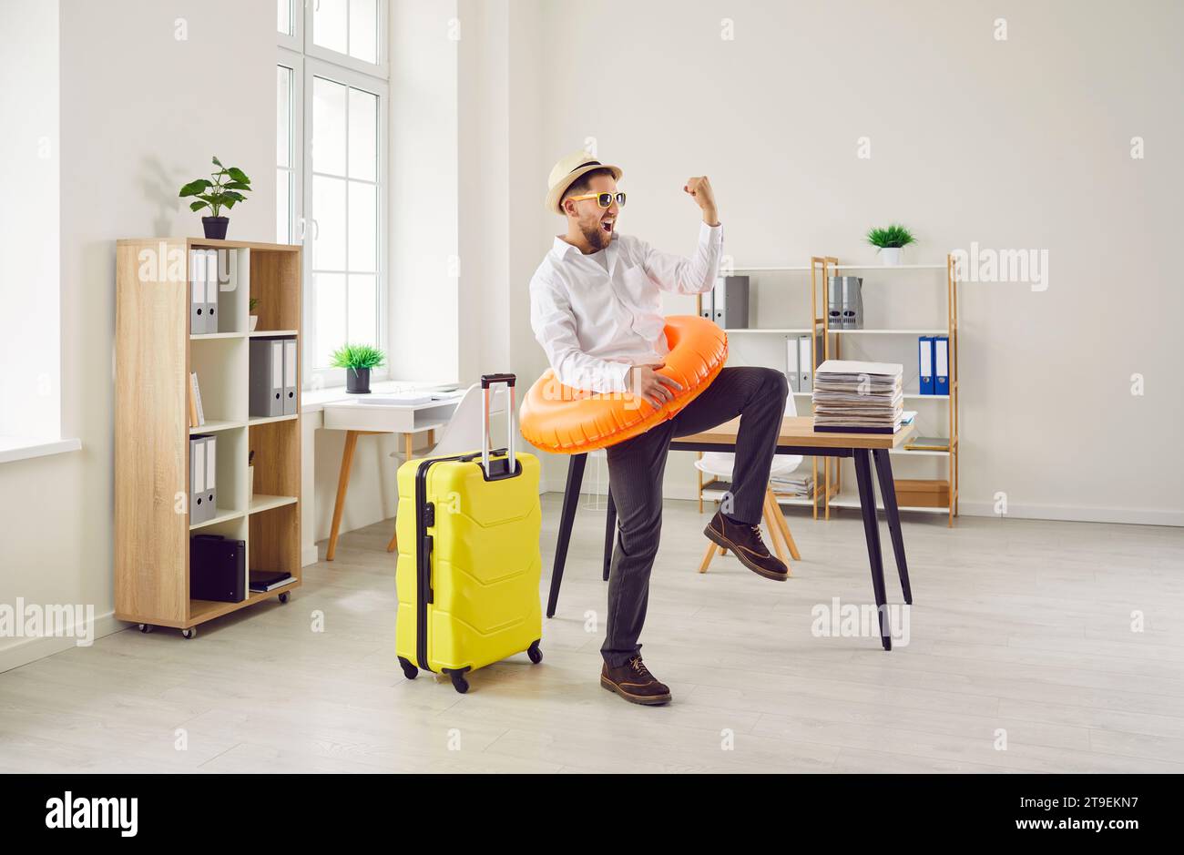 Homme d'affaires heureux avec une valise et un anneau de plage part en vacances et s'amuse au bureau Banque D'Images
