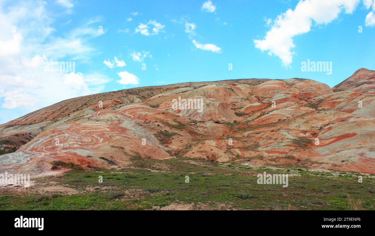 Montagnes avec des rayures rouges et de l'herbe verte. Région de Khizi. Azerbaïdjan. Banque D'Images