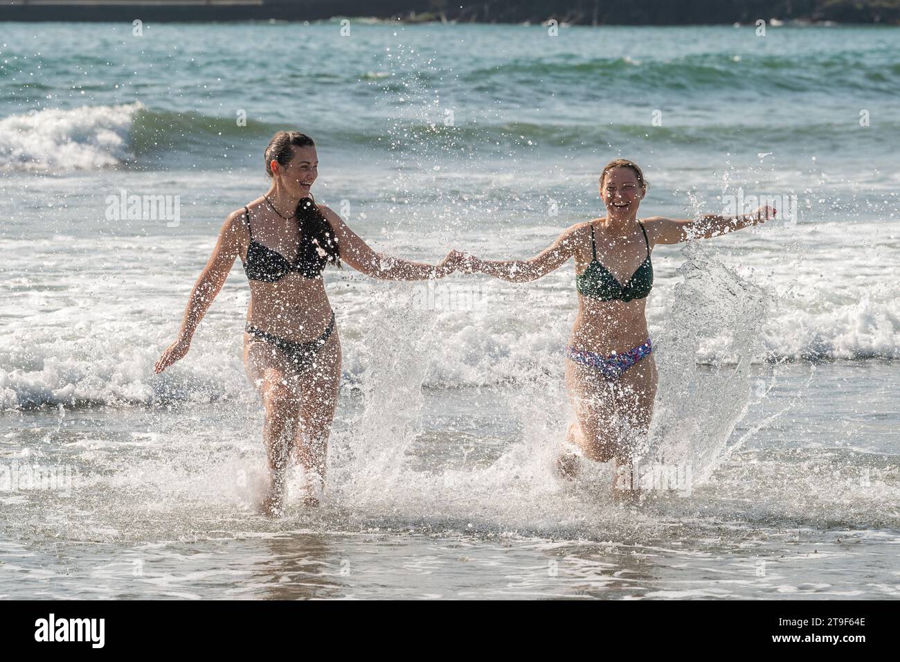 Deux femmes vêtues de bikini s'amusent dans la mer à Warren Beach, Rosscarbery, West Cork, Irlande. Banque D'Images