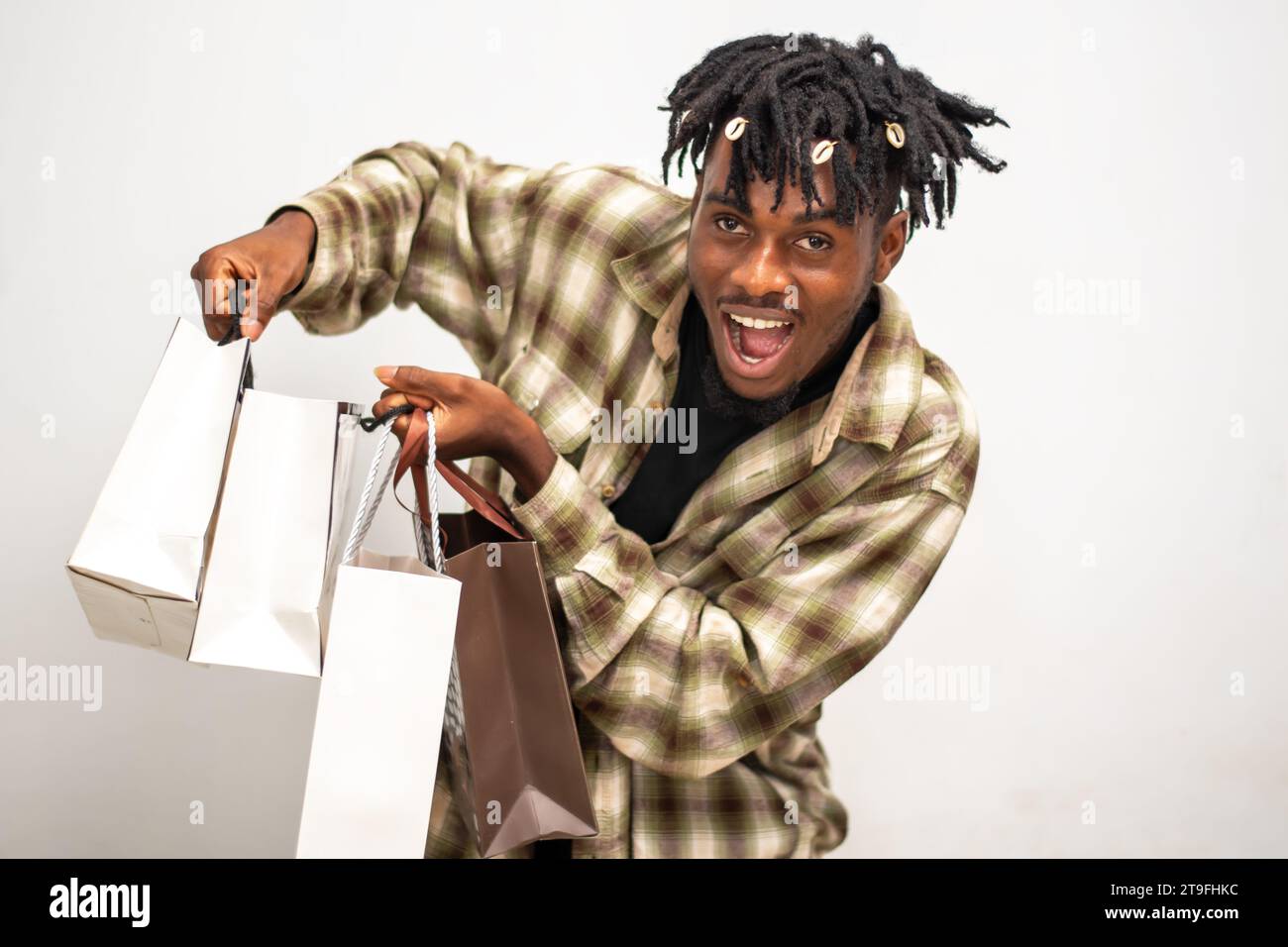 Homme africain avec des sacs à main excité après la frénésie de shopping. Jeune gars sur dreadlocks tenant des sacs avec des vêtements à vendre achat le Black Friday Banque D'Images