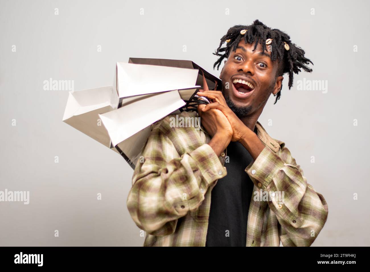Homme africain avec des sacs à main excité après la frénésie de shopping. Jeune gars sur dreadlocks tenant des sacs avec des vêtements à vendre achat le Black Friday Banque D'Images
