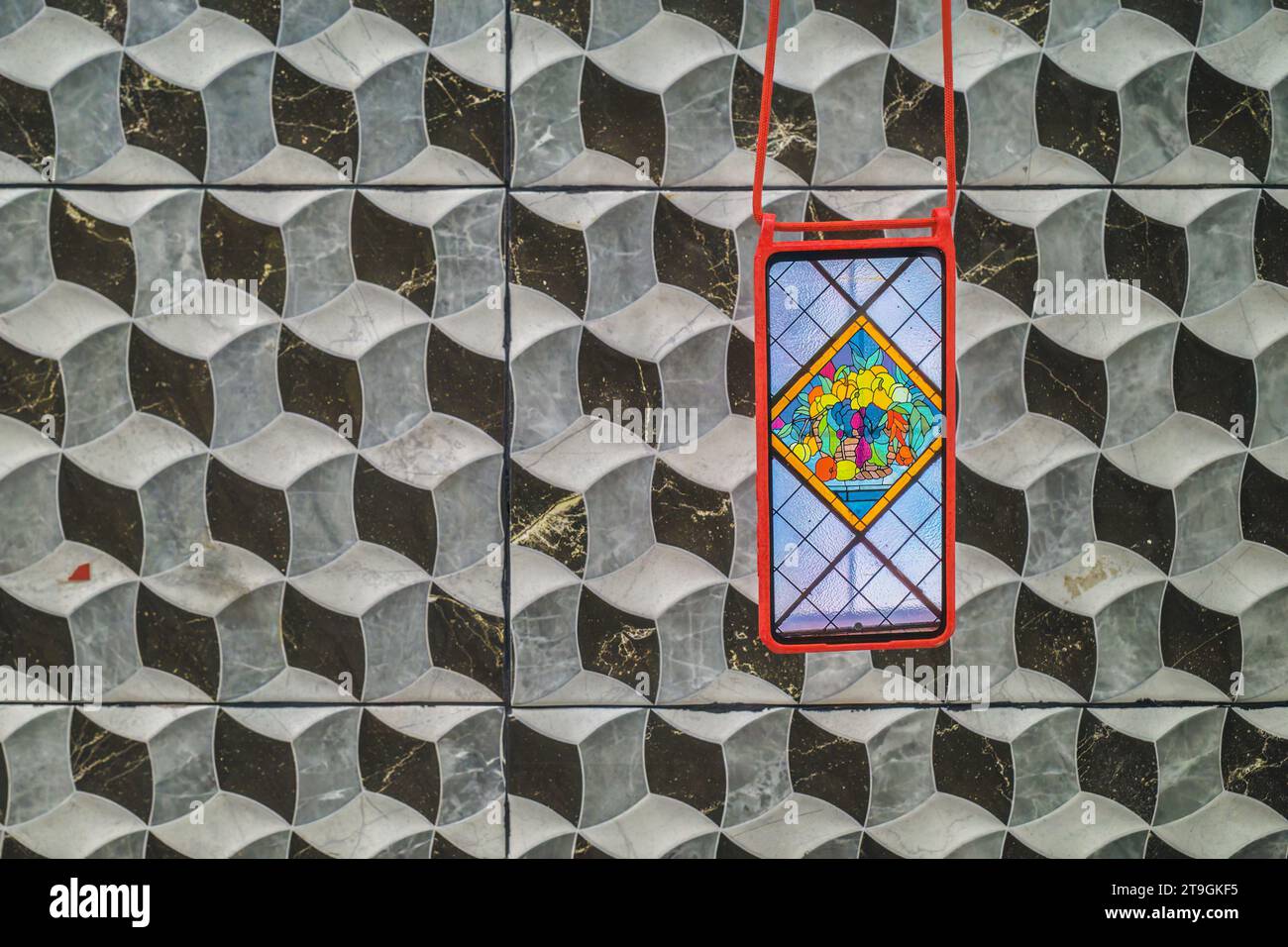 Téléphone portable allumé avec une photo couleur de fruits sur un fond de cubes en relief avec rythme et motif en blanc et gris sur un mur à Burriana Banque D'Images