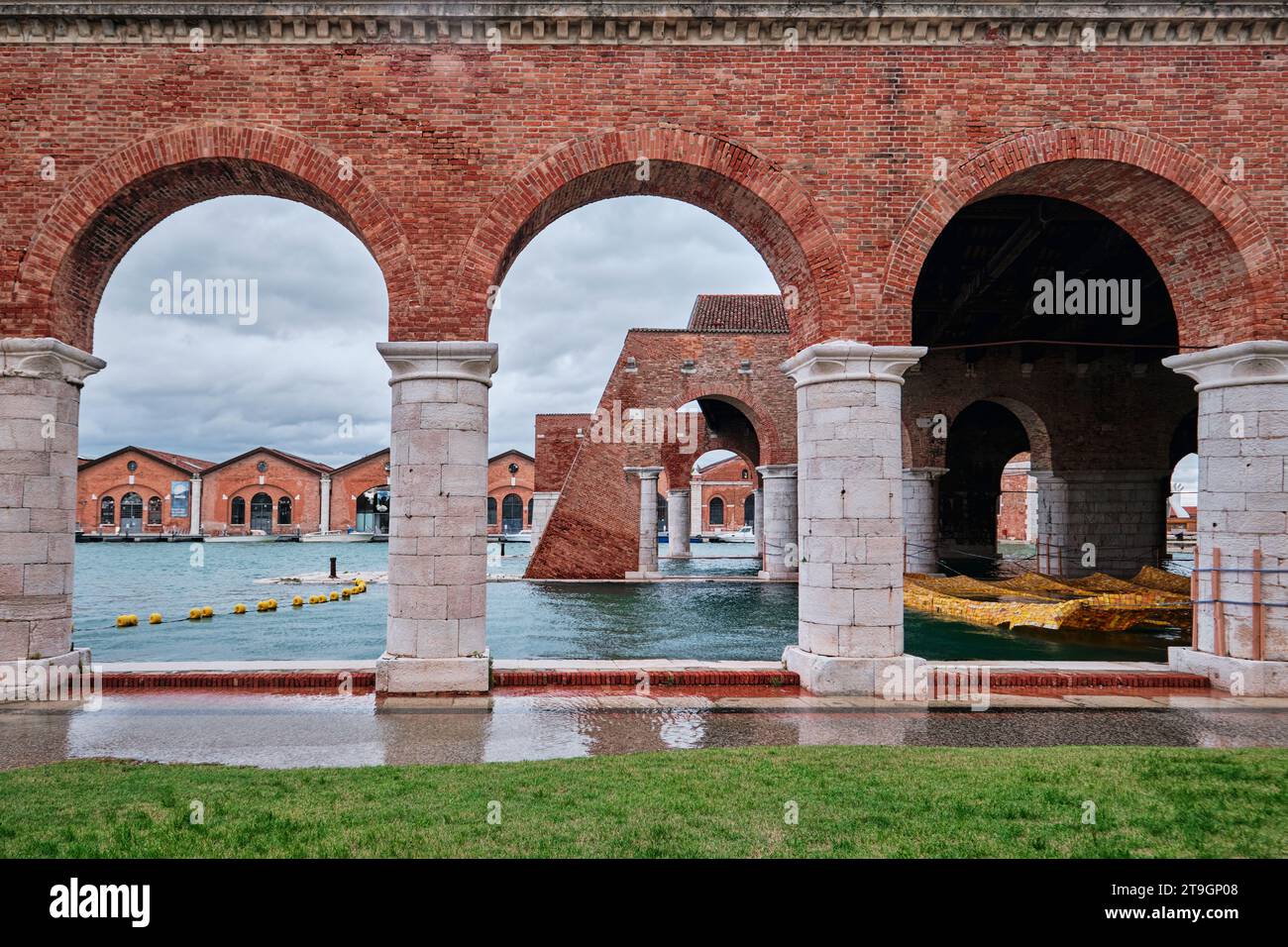 Venise, Italie - novembre 9 2023 : Arsenal vénitien avec arcade, canal et herbe verte par jour de pluie Banque D'Images