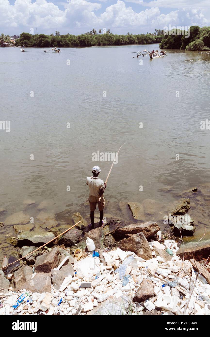 Un homme pêche parmi les ordures sur les rives d'une rivière près de Negombo au Sri Lanka Banque D'Images