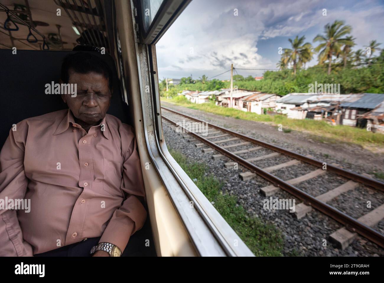 Un homme dort sur le siège près de la fenêtre dans un train quittant Colombo au Sri Lanka Banque D'Images