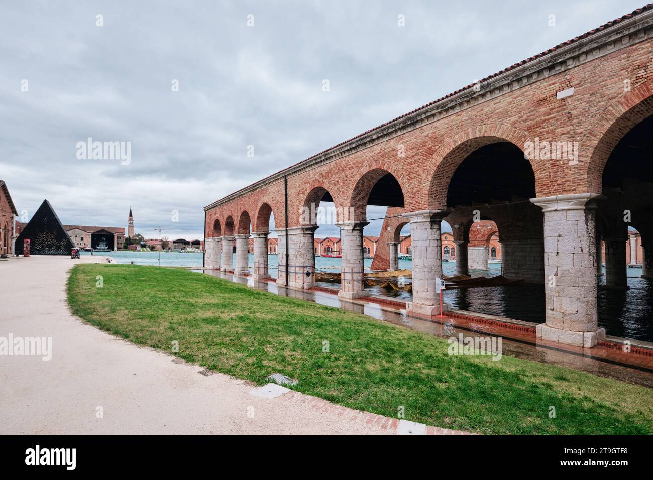 Venise, Italie - novembre 9 2023 : Arsenal vénitien avec arcade, canal et herbe verte par jour de pluie Banque D'Images