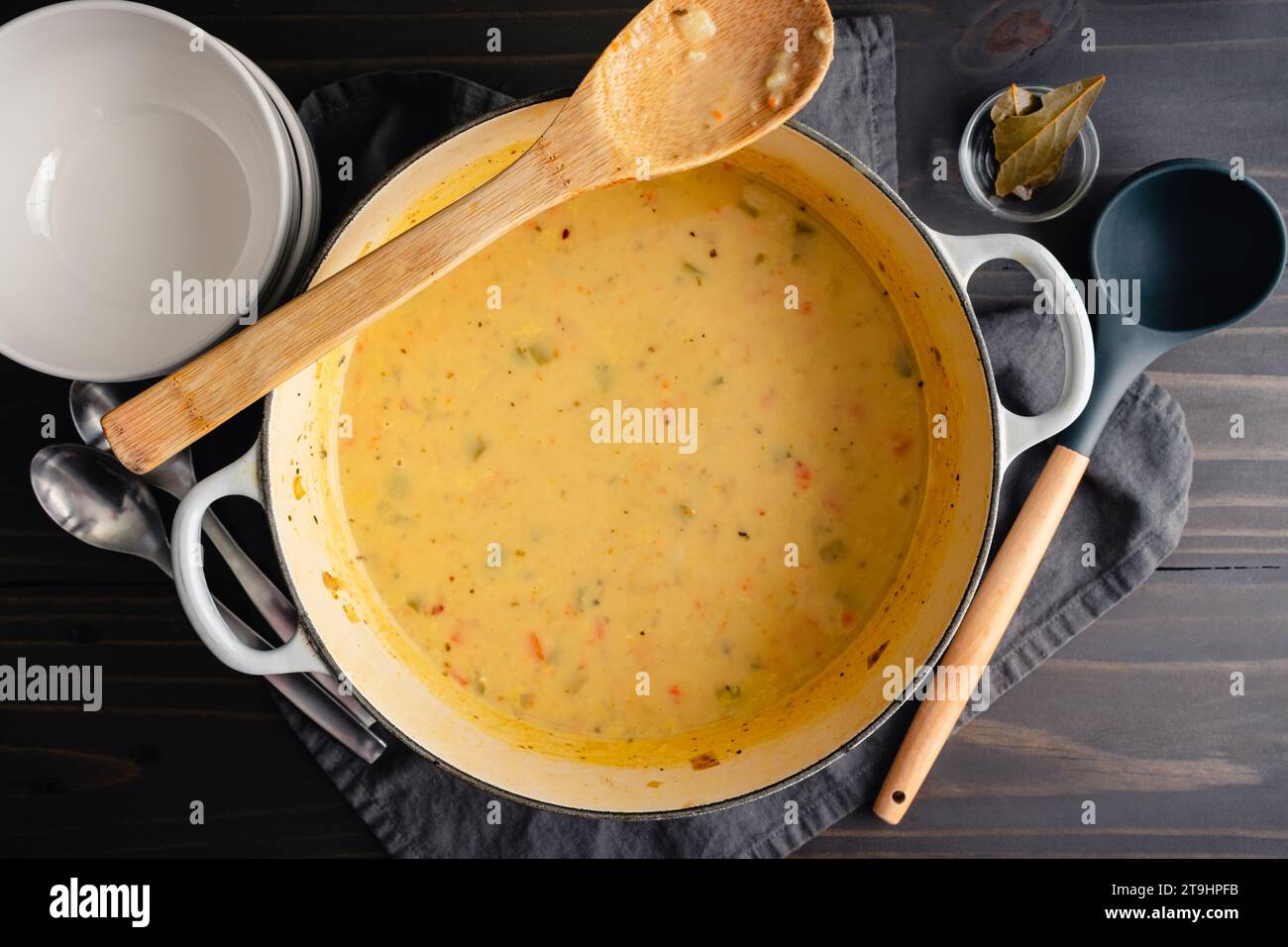 Soupe allemande de pommes de terre maison (Kartoffelsuppe) dans un four hollandais : soupe crémeuse de légumes dans une casserole en fonte avec des bols à soupe et des cuillères sur le côté Banque D'Images