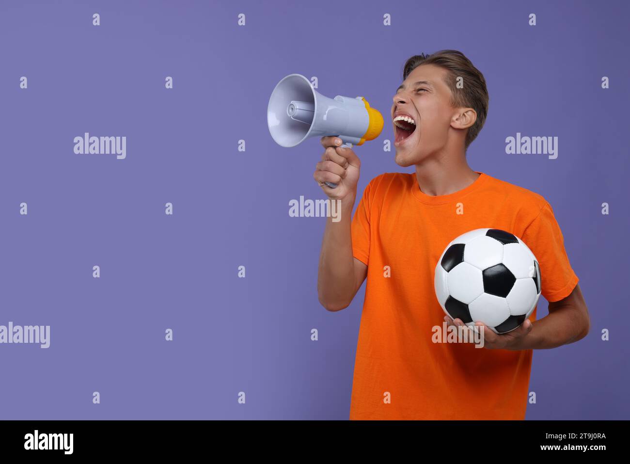 Fan de sport avec ballon de football criant en mégaphone sur fond violet. Espace pour le texte Banque D'Images