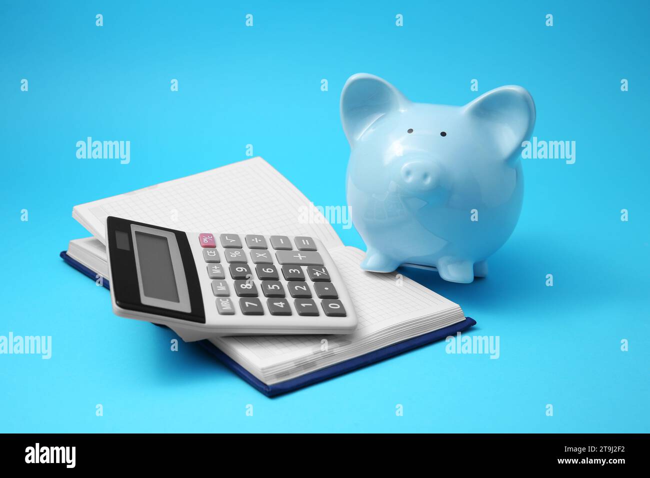 Tirelire, cahier et calculatrice sur fond bleu clair Banque D'Images