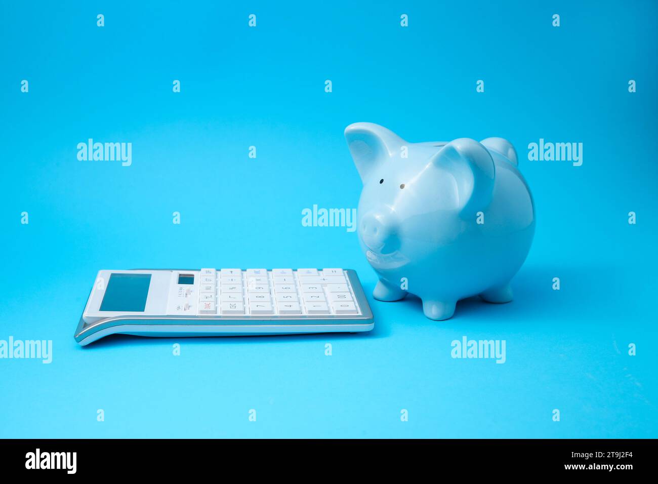 Tirelire et calculatrice sur fond bleu clair Banque D'Images