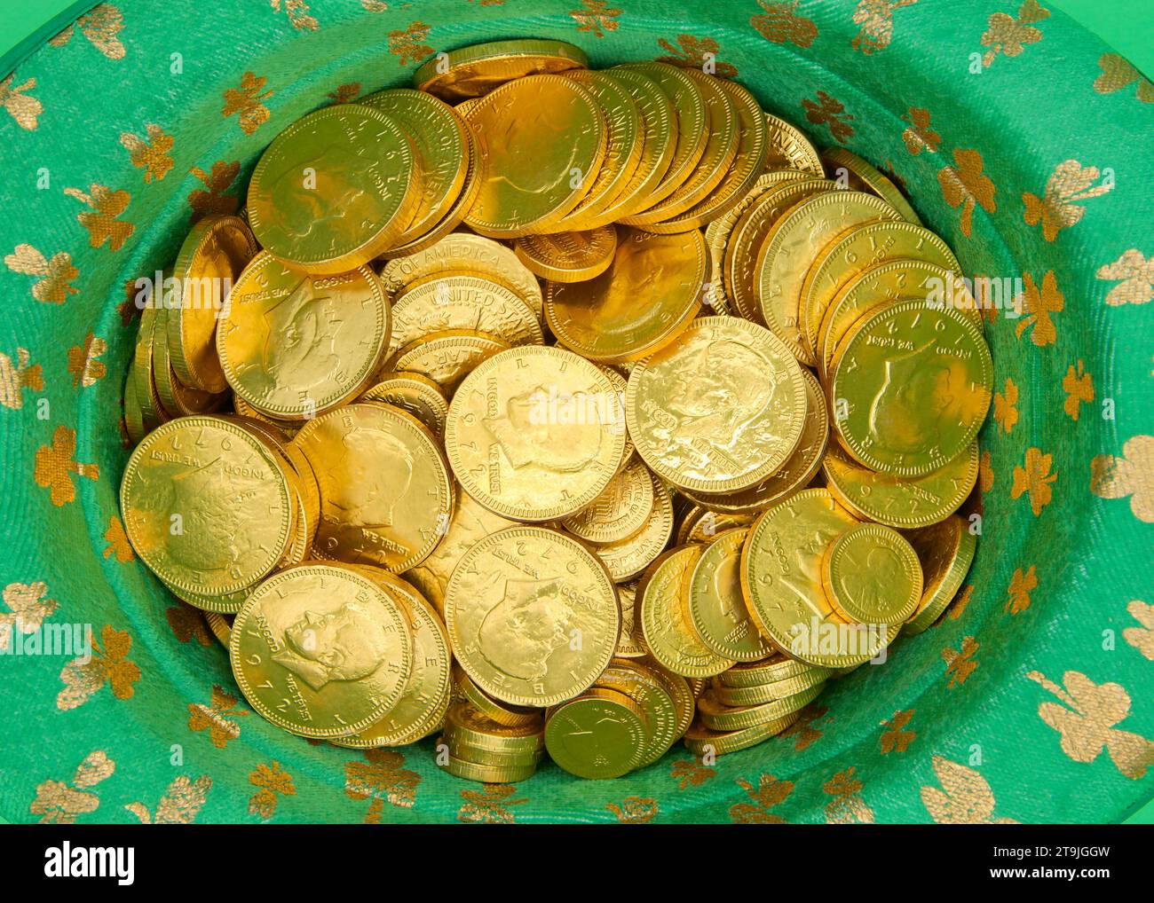 Vue de dessus du chapeau vert Saint Patricks Day avec des trèfles d'or remplis de pièces d'or brillantes. Banque D'Images