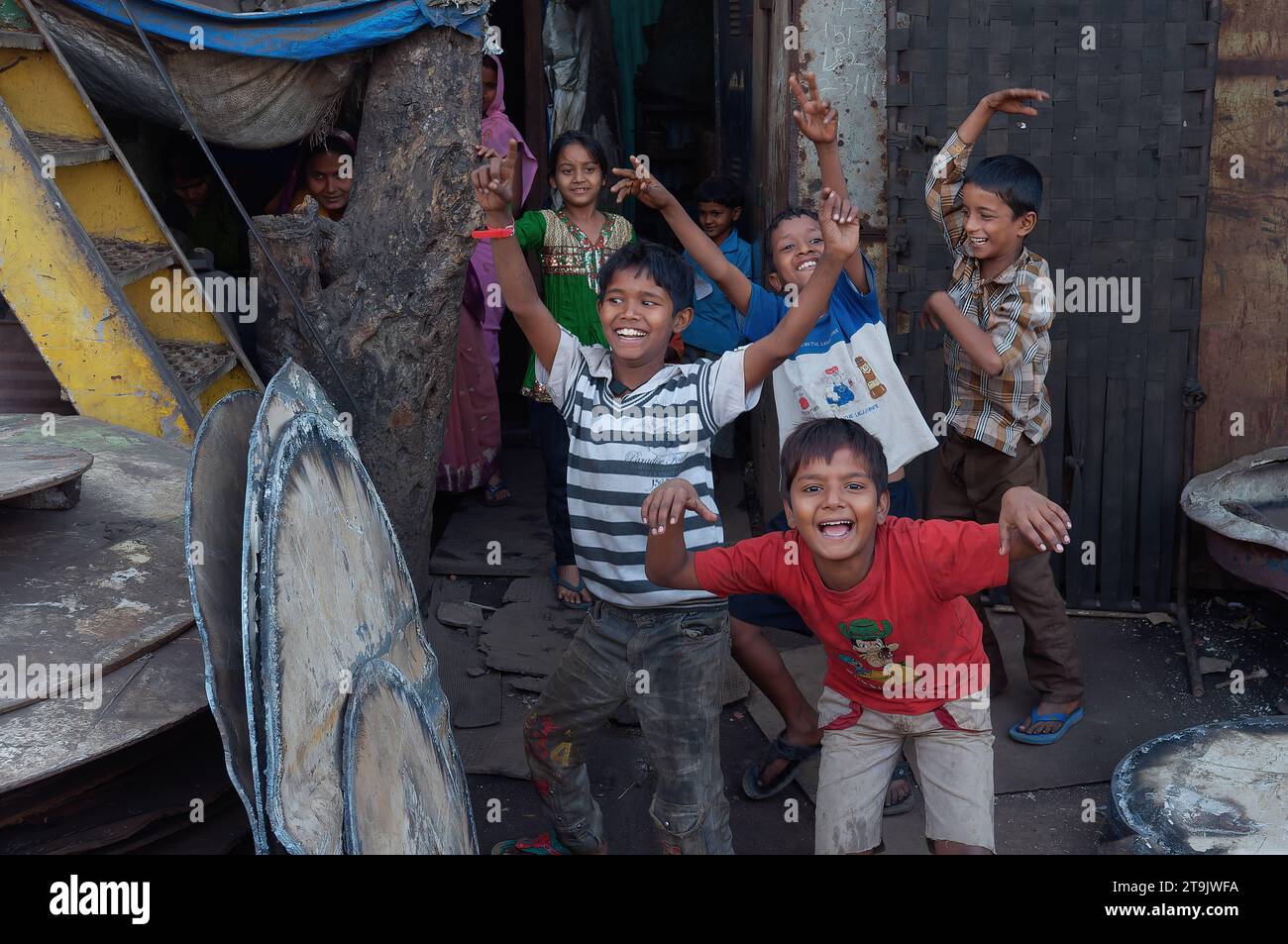 Des enfants joyeux vivant dans le bidonville de Darukhana, Mazagaon, Mumbai, Inde, souriant à la vue d'une caméra et rompant spontanément dans la danse Banque D'Images