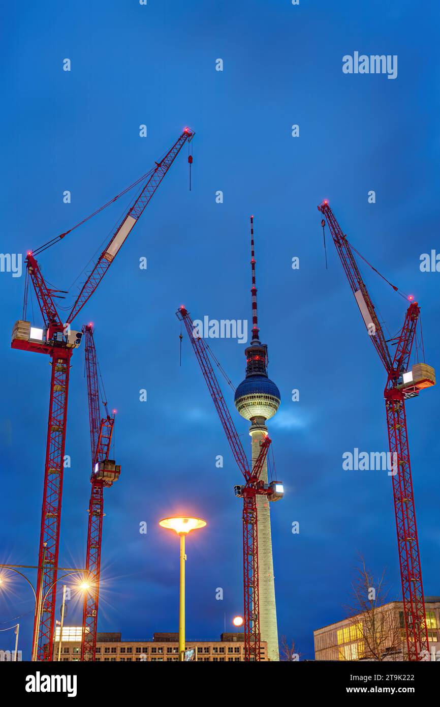 La célèbre tour de télévision de Berlin la nuit avec quatre grues de construction rouges Banque D'Images