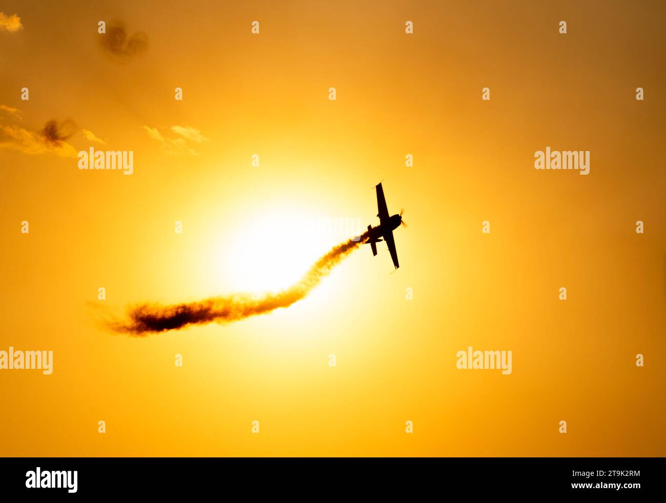 Silhouette d'un avion acrobatique volant au coucher du soleil contre le ciel cramoisi. Banque D'Images