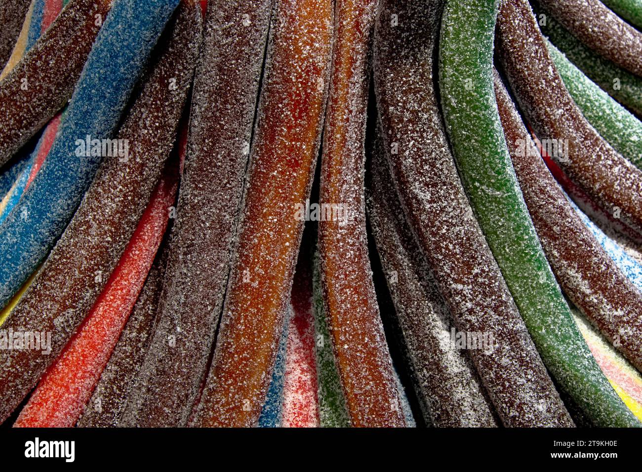 Gros plan de cordes de bonbons colorées. Ils sont tordus, enrobés de sucre, et viennent en rouge, bleu, vert et brun. Banque D'Images