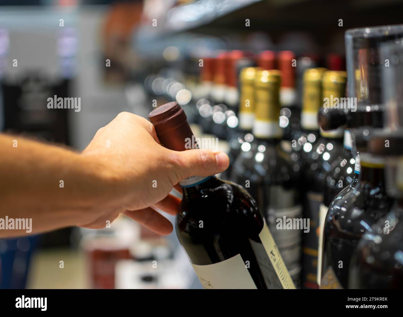 Main prenant bouteille de vin stocké sur le supermarché pour la vente et prêt à la consommation Banque D'Images