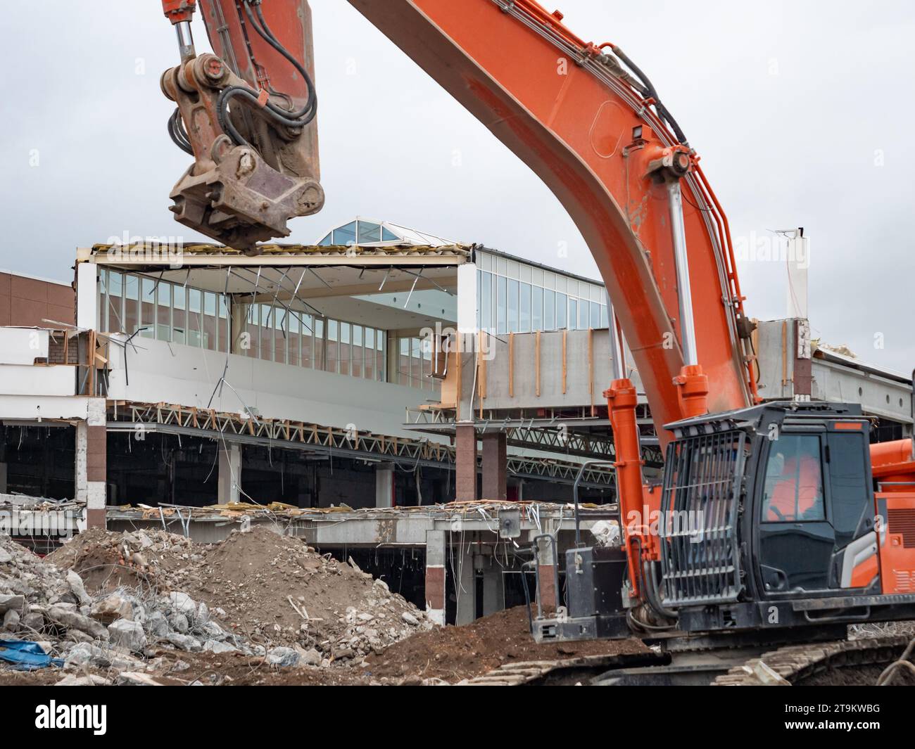Démolition d'un bâtiment de centre commercial avec une grosse excavatrice. Détruire une vieille maison pour faire de la place pour un nouveau chantier de construction. Tas de saleté Banque D'Images