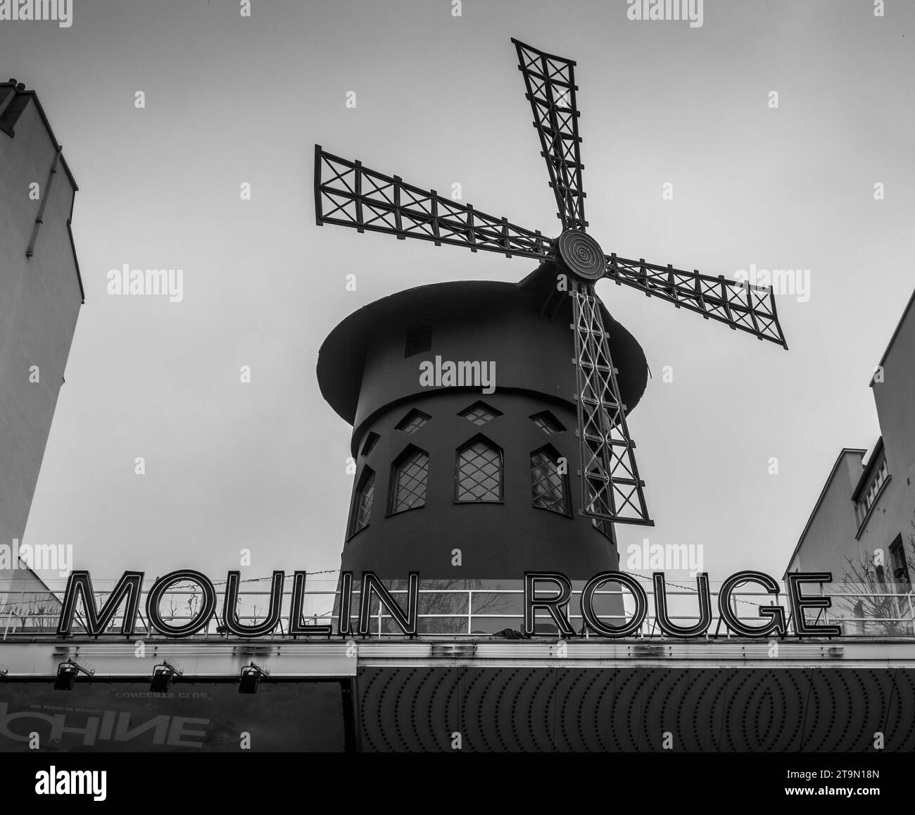 Photographie en noir et blanc très contrastée d'un moulin à vent néerlandais traditionnel situé au sommet d'un bâtiment en briques Banque D'Images