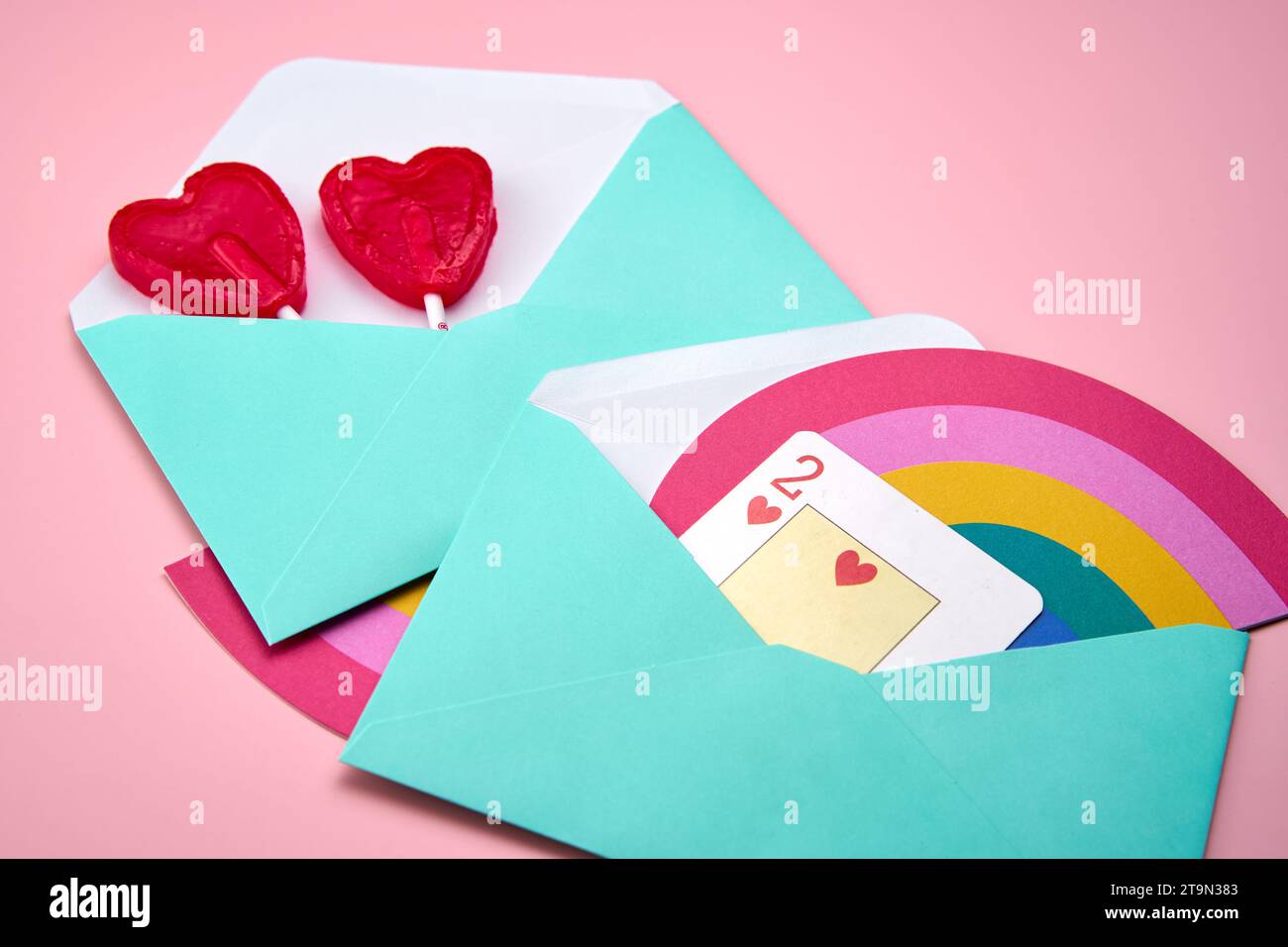 Lettres d'amour avec des sucettes arc-en-ciel et en forme de coeur sur un fond rose Banque D'Images