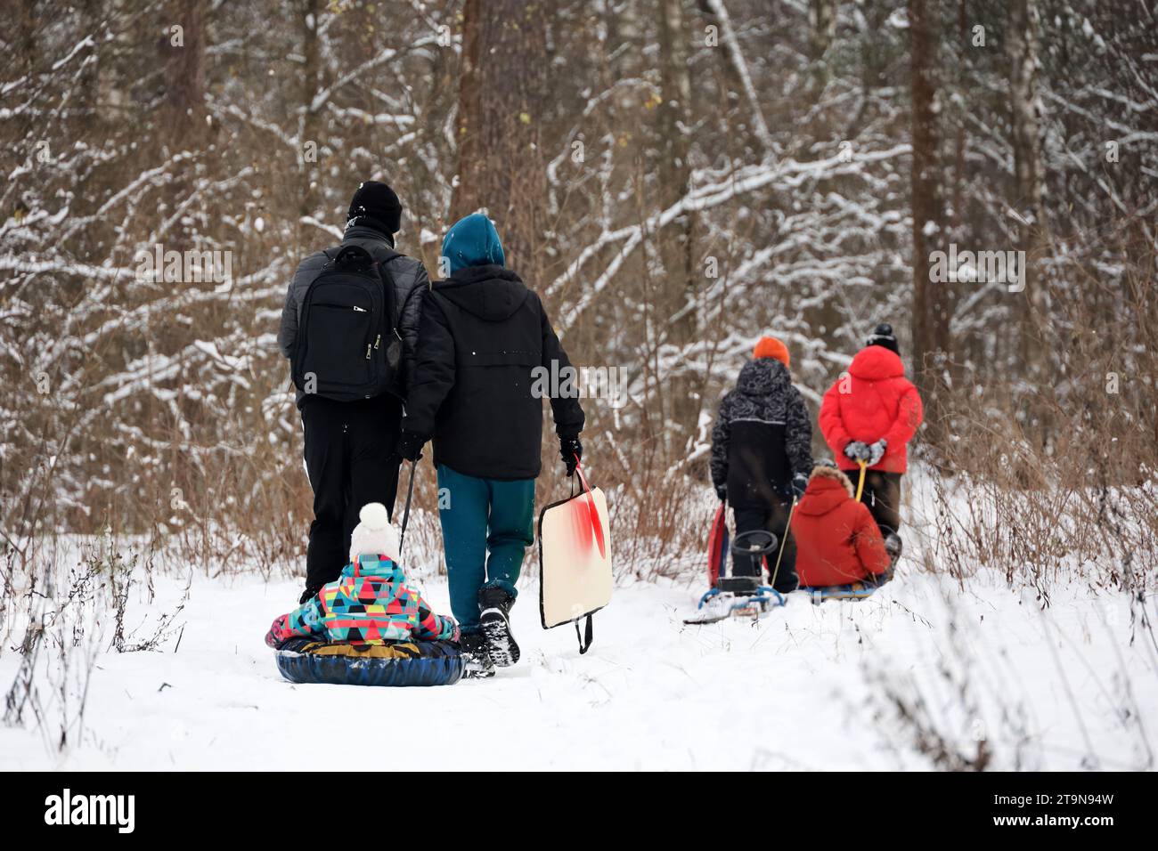 Loisirs en famille sur la nature hivernale, couple avec enfants se rendent au parc pour rouler sur des tubes à neige Banque D'Images