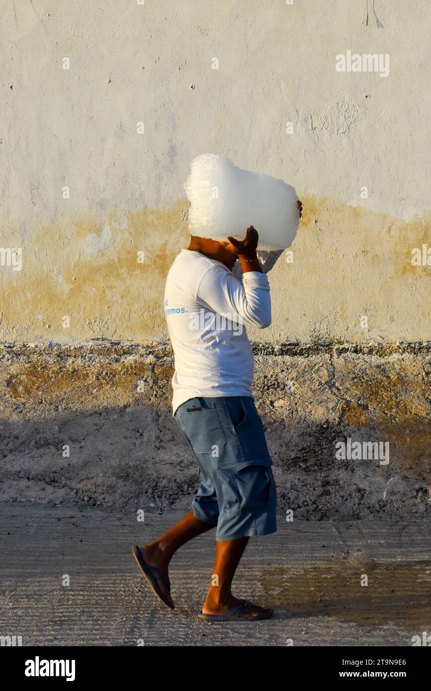 Pêcheur transportant un bloc de glace dans le village de pêcheurs d'El Cuyo, Yucatan, mexique Banque D'Images