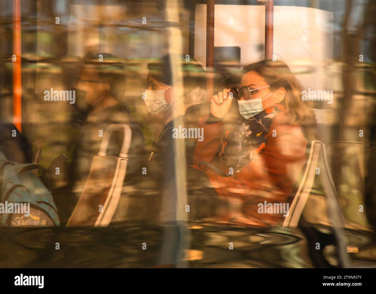 Belgrade, Serbie- 18 mars 2022 : passagers de personnes voyageant dans un bus de ville le jour ensoleillé, avec la lumière du soleil et les reflets de couleurs de la ville sur la fenêtre Banque D'Images