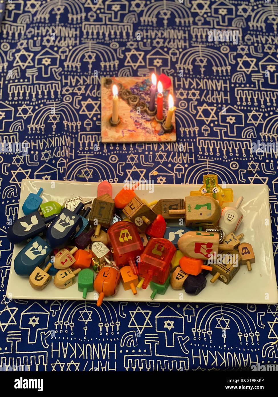 ÉTATS-UNIS. 12 décembre 2020. La 3e nuit de Chanucha plus la bougie shamash (aide) sur une menorah. Une assiette de Draidels - un jeu traditionnel à jouer pendant Hanukkah. Souvent, les enfants jouent pour des bonbons de monnaie de chocolat ou de l'argent. Crédit photo : Robyn Stevens Brody/Sipa USA. Crédit : SIPA USA/Alamy Live News Banque D'Images