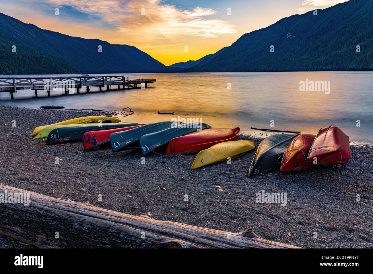 Des canoës et des kayaks colorés bordent la rive du lac Crescent dans le parc national olympique en fin de soirée alors que le soleil se couche sur l'eau calme Banque D'Images