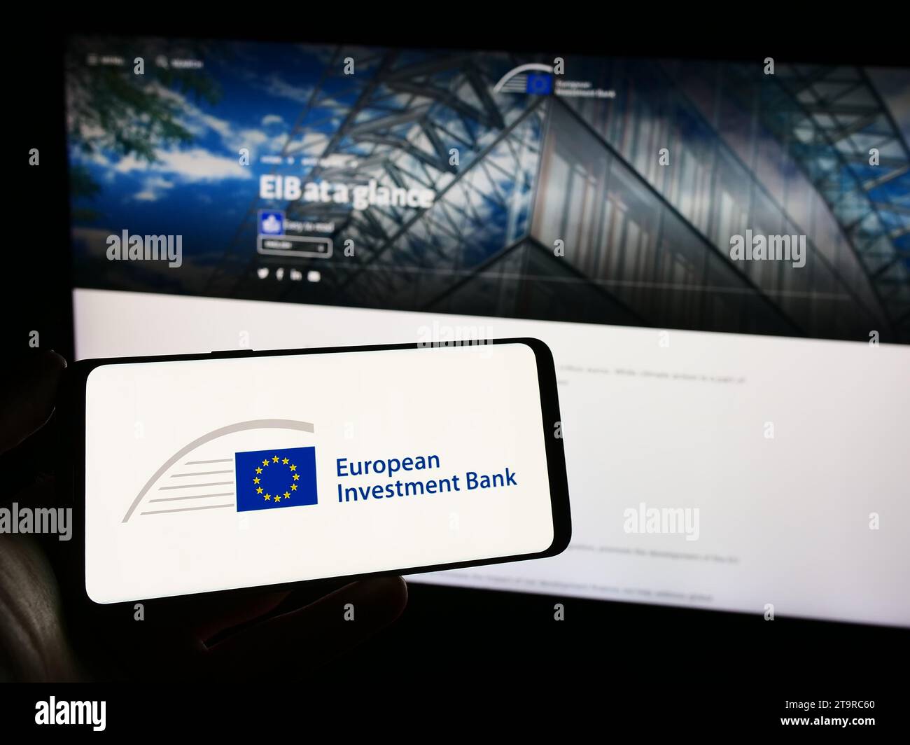 Titulaire d'un téléphone portable portant le logo de l'institution financière de l'UE Banque européenne d'investissement (BEI) devant la page Web. Concentrez-vous sur l'affichage du téléphone. Banque D'Images