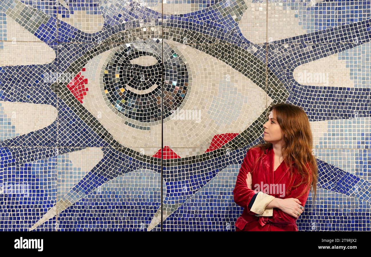 Un membre du personnel regarde la mosaïque psychédélique de John Lennon, commandée pour la piscine de son domicile à Kenwood, Surrey, qui est exposée à la maison de vente aux enchères Bonhams à Kinghtsbridge, Londres, avant la vente Rock, Pop et film mercredi. Composée d'environ 17 000 tuiles, la mosaïque a été créée par Joseph Ritrovato, un maître carreleur qui l'a installé à lui seul sur le mur profond de la piscine de John Lennon à Kenwood dans le Surrey, dont il était propriétaire de juillet 1964 à la fin du printemps 1968. Date de la photo : lundi 27 novembre 2023. Banque D'Images