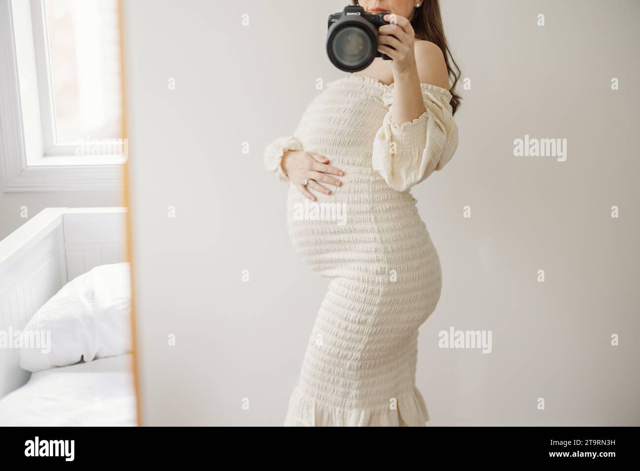 Autoportrait d'une femme enceinte en robe de maternité embrassant le ventre Banque D'Images