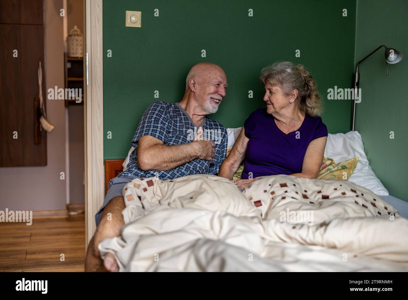 Couple âgé assis dans le lit et se regardant avec amour Banque D'Images