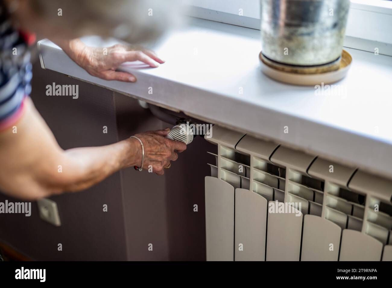 Femme âgée vérifiant la température sur un radiateur de chauffage dans la cuisine à la maison Banque D'Images