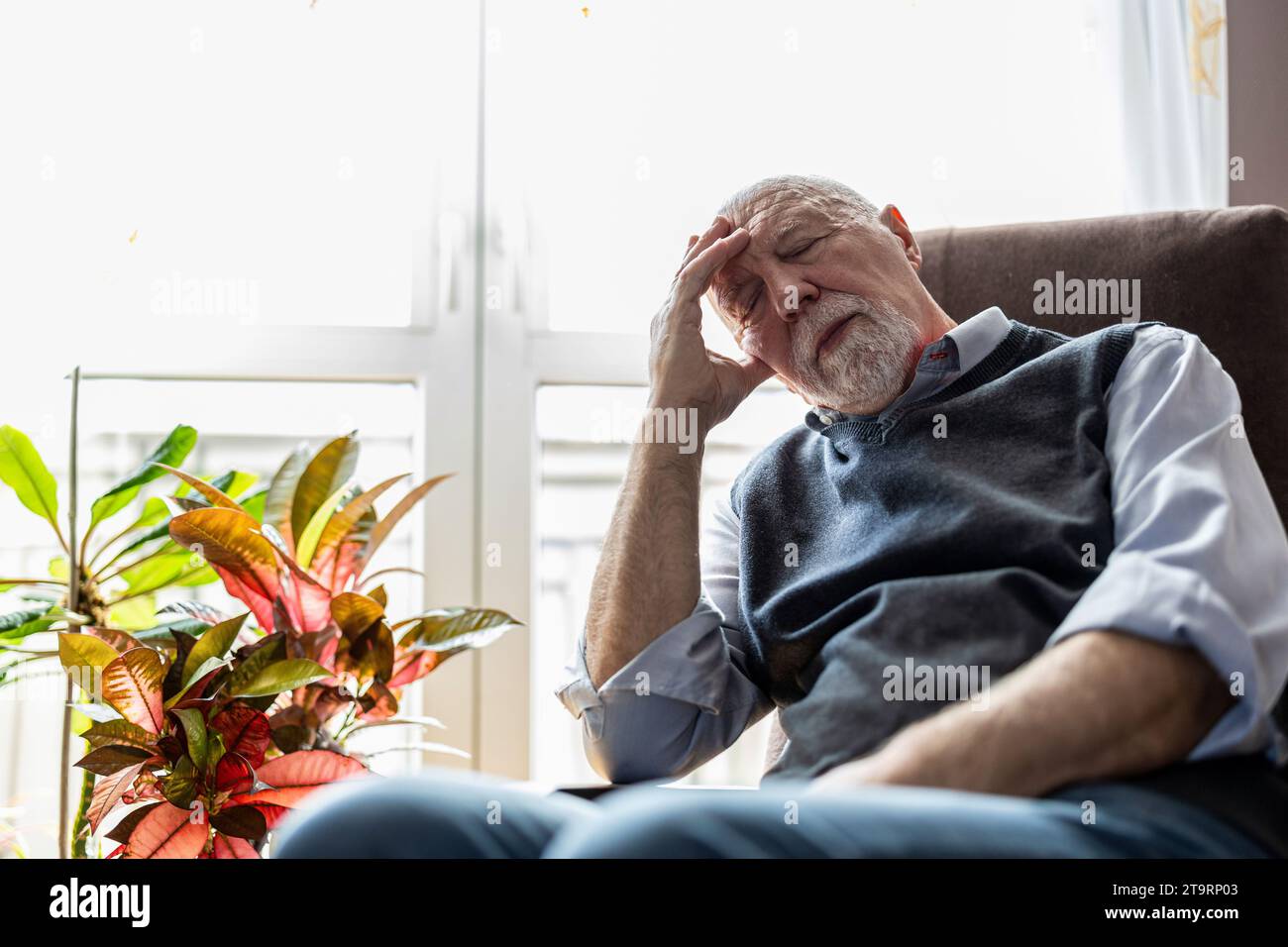 Homme senior dormant dans un fauteuil à la maison Banque D'Images