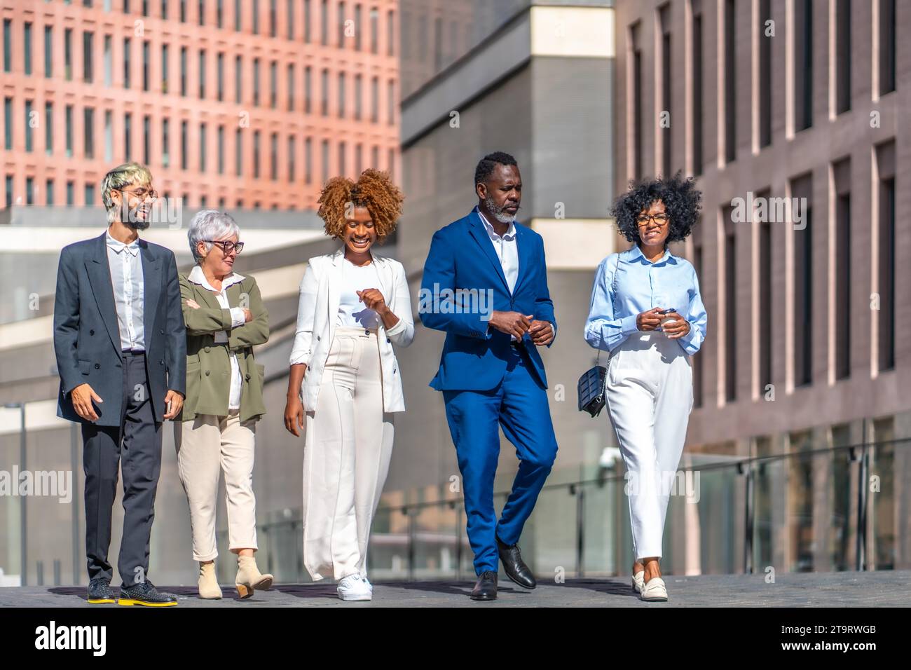 Des gens d'affaires multiculturels marchent et parlent dans la rue de la ville à côté de certains bâtiments financiers Banque D'Images