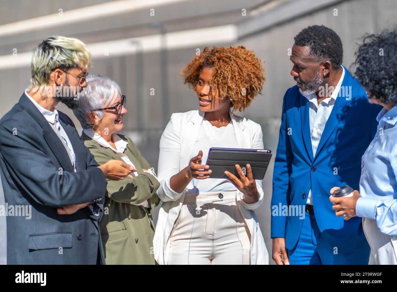 Femme d'affaires africaine utilisant la tablette tout en expliquant un projet à des collègues dans une réunion d'affaires en plein air Banque D'Images