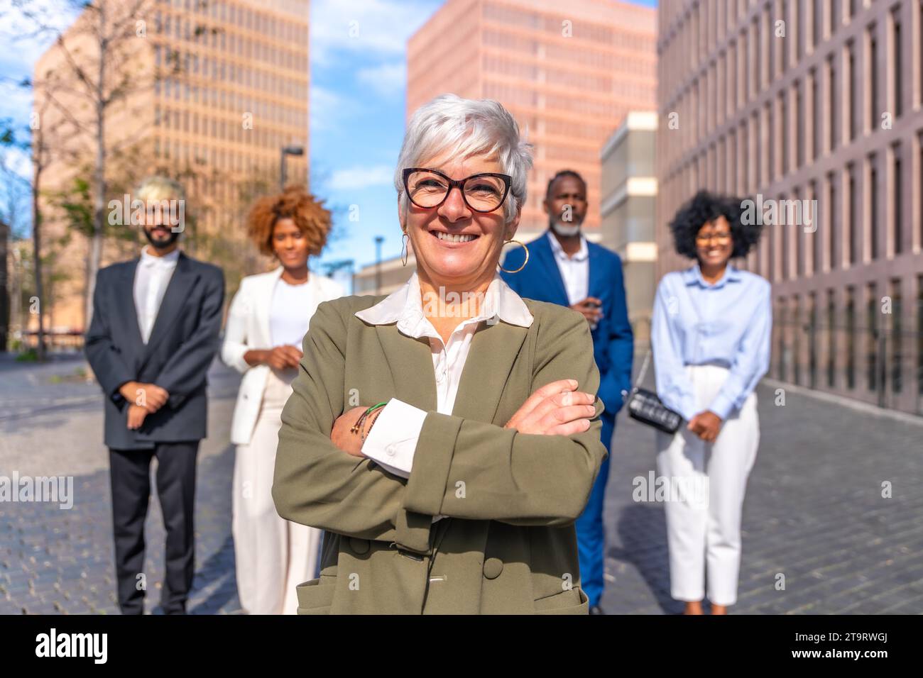 Photo rapprochée frontale d'une femme d'affaires mûre et souriante se tenant fière à côté de ses collègues Banque D'Images