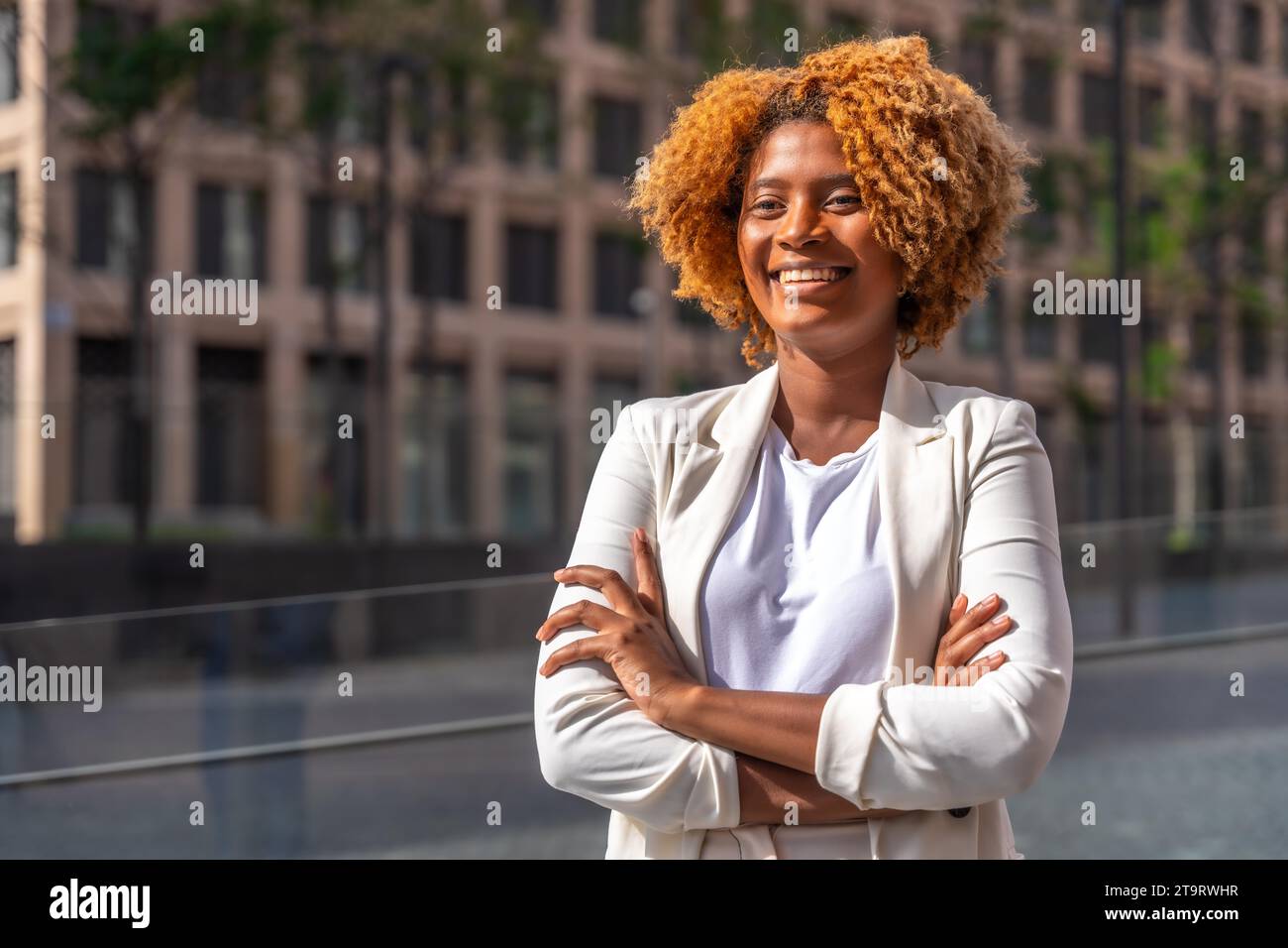 Jeune femme d'affaires africaine debout fière avec les bras croisés dans la rue de la ville Banque D'Images