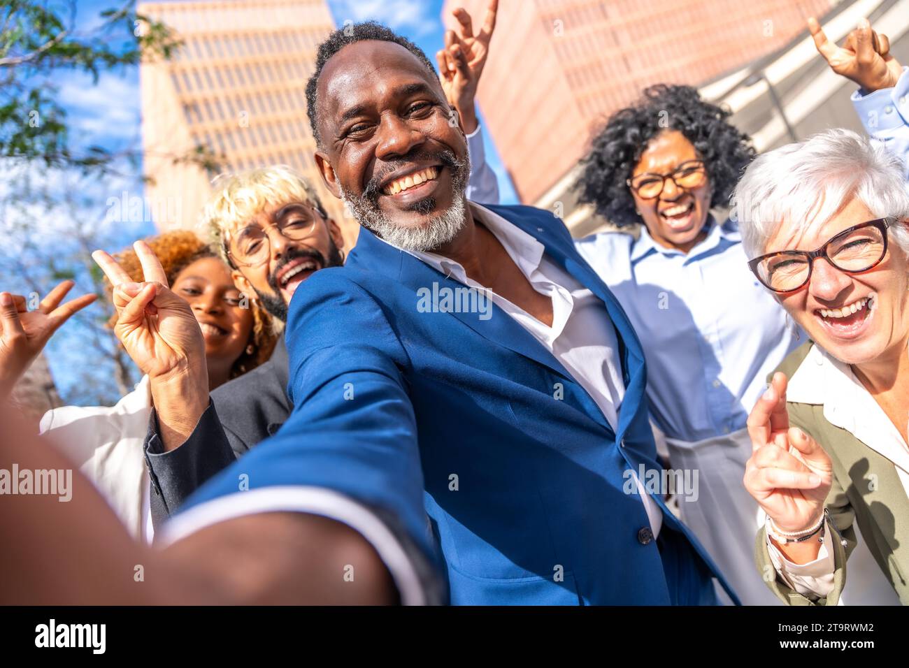 Vue frontale de mignon élégant homme d'affaires africain prenant un selfie avec des collègues à l'extérieur Banque D'Images