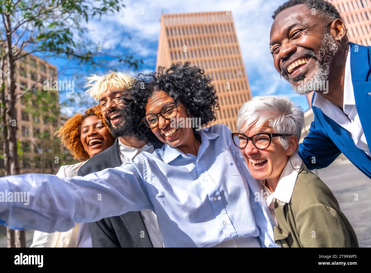 Amis d'affaires multi-ethniques souriant et prenant un selfie à l'extérieur Banque D'Images