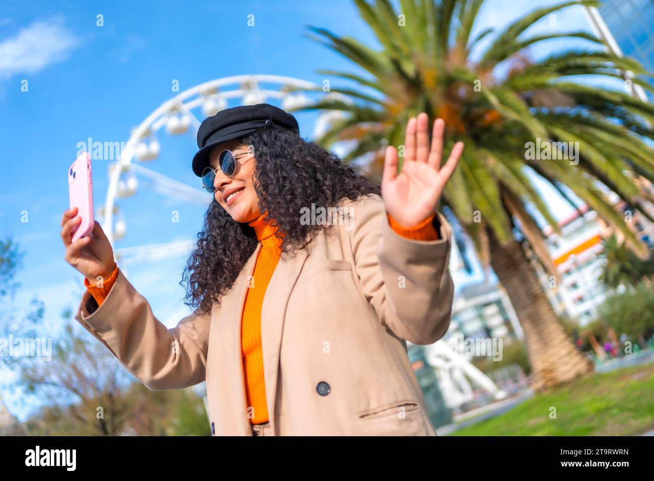 Femme posant tout en prenant un selfie dans la ville pendant une chaude journée d'hiver Banque D'Images