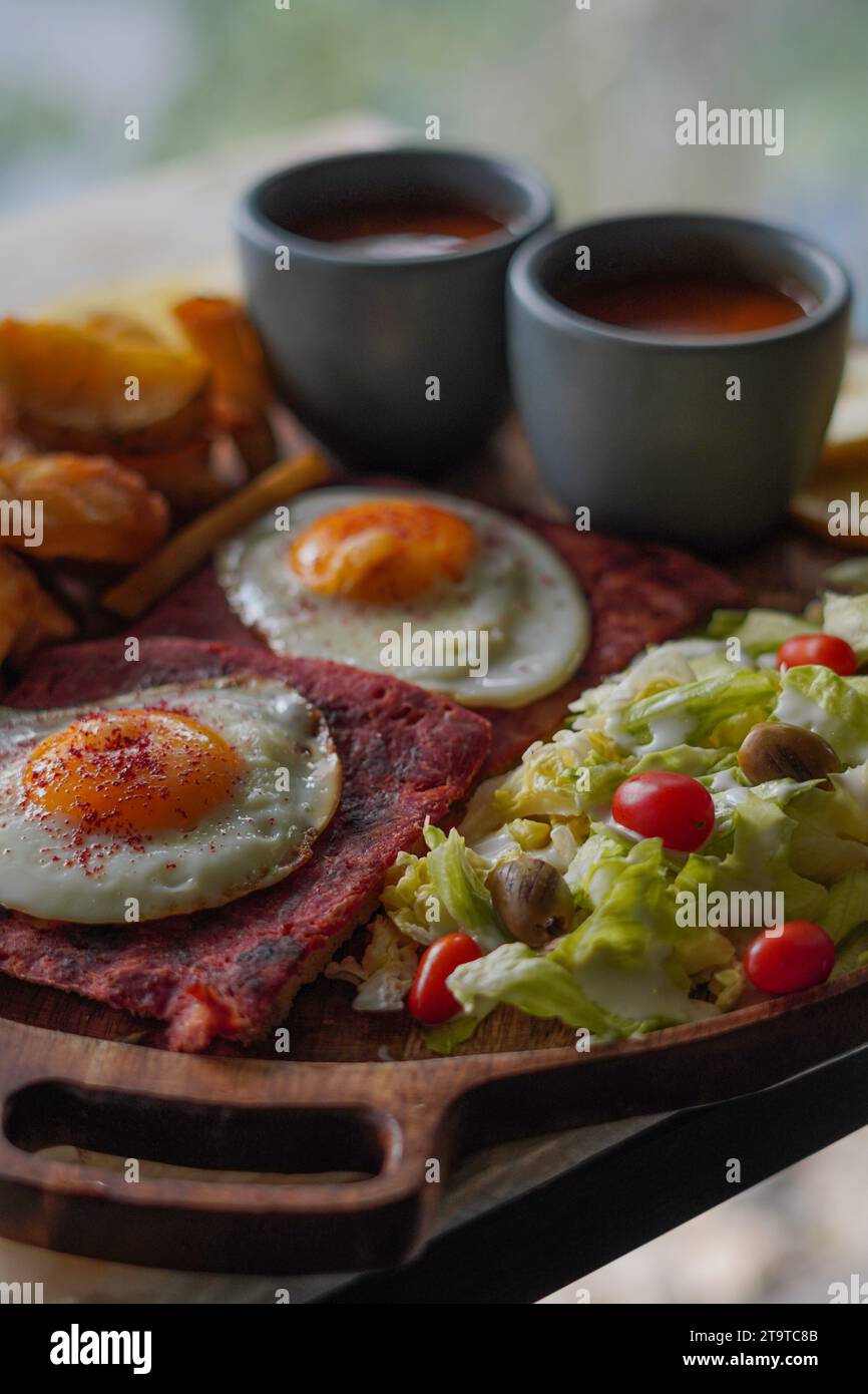 Petit déjeuner anglais, sur un grand plateau en bois, œufs, bologne, pommes de terre et haricots. Banque D'Images