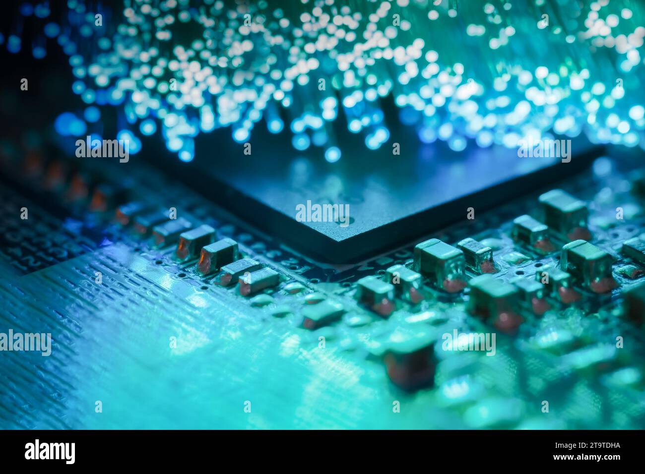 Macro-photographie d'une carte de circuit imprimé avec un processeur et des fibres optiques éclairant la carte Banque D'Images