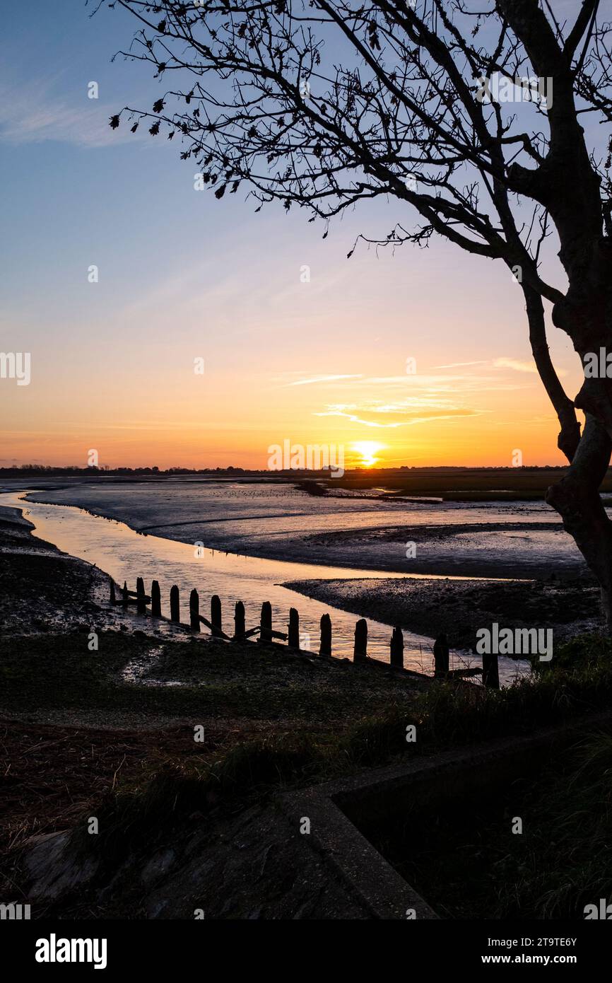 Coucher de soleil à Pagham Harbour RSPB réserve naturelle à marée basse sur un après-midi d'automne , West Sussex , Angleterre Royaume-Uni Banque D'Images