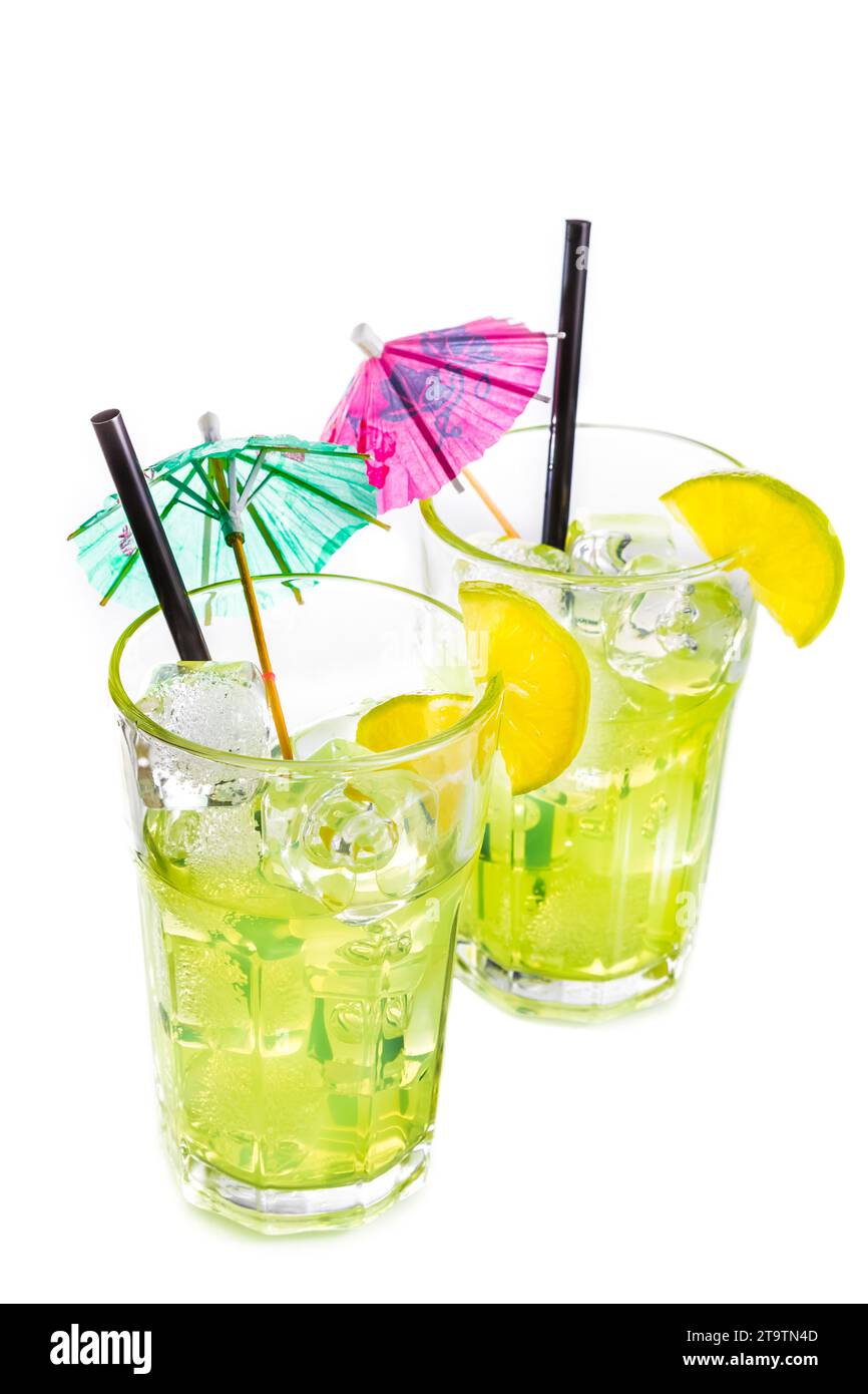 vue de dessus de deux verres avec cocktail et glace avec tranche de citron vert et parapluie cocktail sur fond blanc, concept d'été disco Banque D'Images